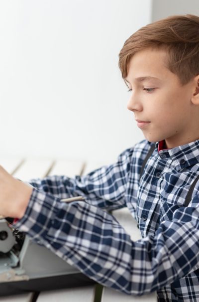 people, children and style concept - young boy with old black typewriter on white background.